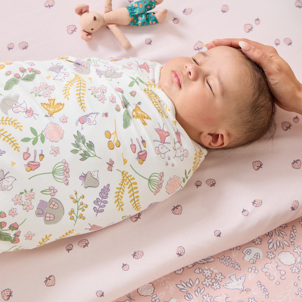 Baby peacefully sleeping swaddled in Tiny Tails muslin with woodland print