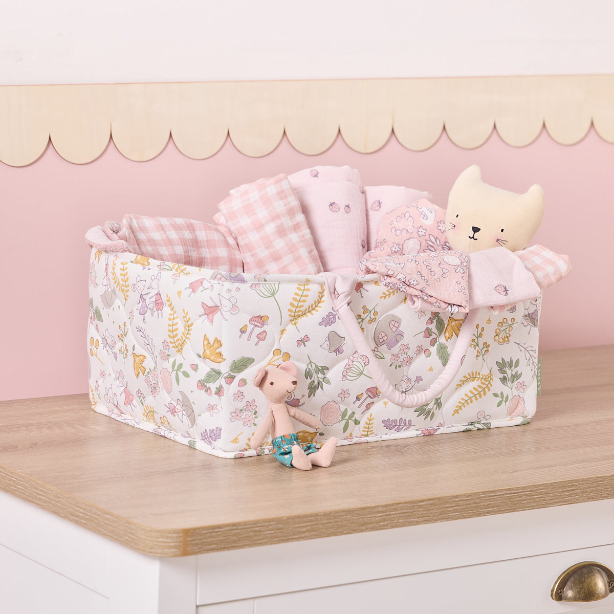 Tiny Tails nappy caddy in pink woodland print filled with soft pink muslins and toys, adding charm and organisation to the nursery
