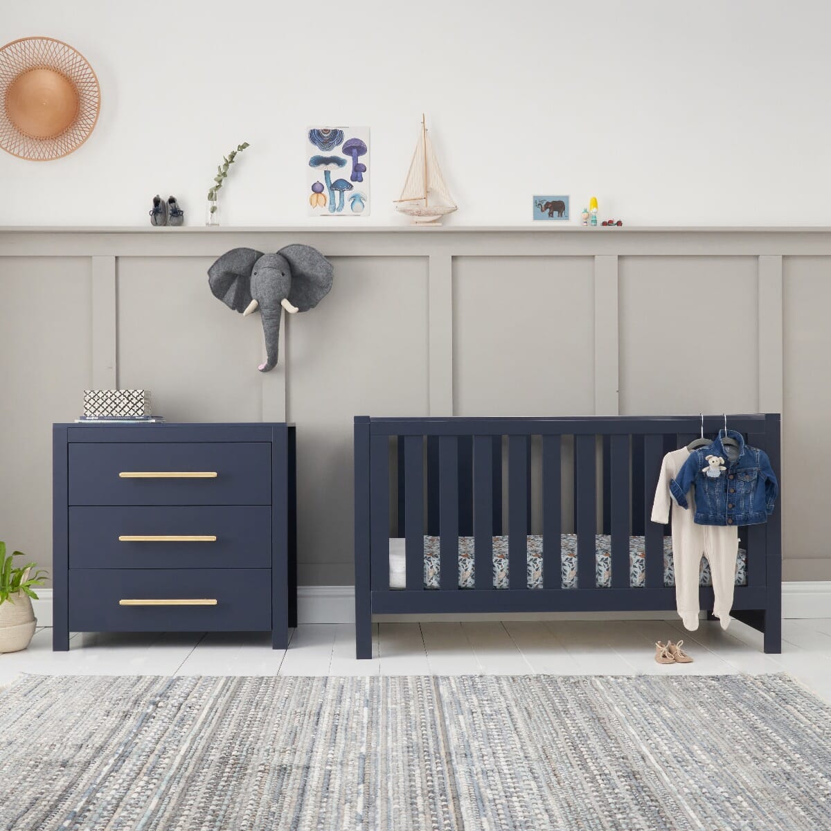 Lifestyle view of the Tivoli navy cot bed and chest changer, styled with playful decor to create a bright, calming nursery for everyday routines