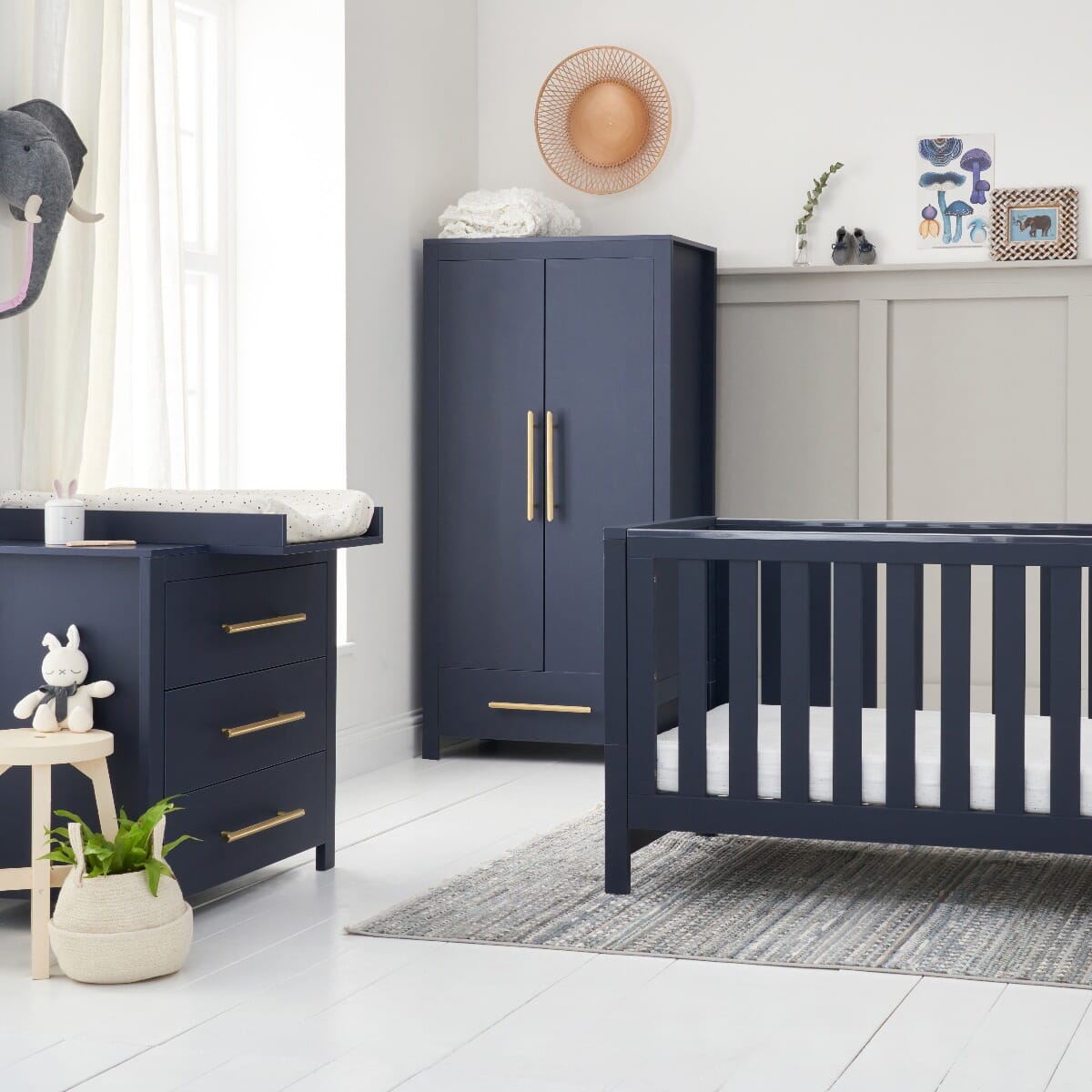 A tivoli three-piece nursery furniture set in navy blue color, including a cot, a wardrobe and chest changer complete with changing top