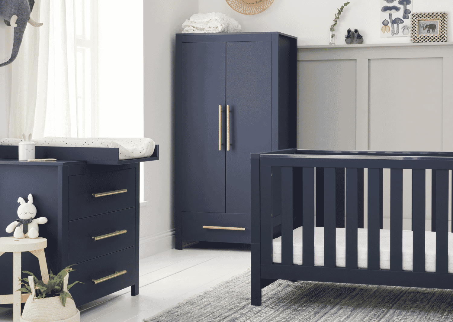 A navy blue Tivoli wardrobe with brushed metallic handles, placed in a room with cot bed and chest changer