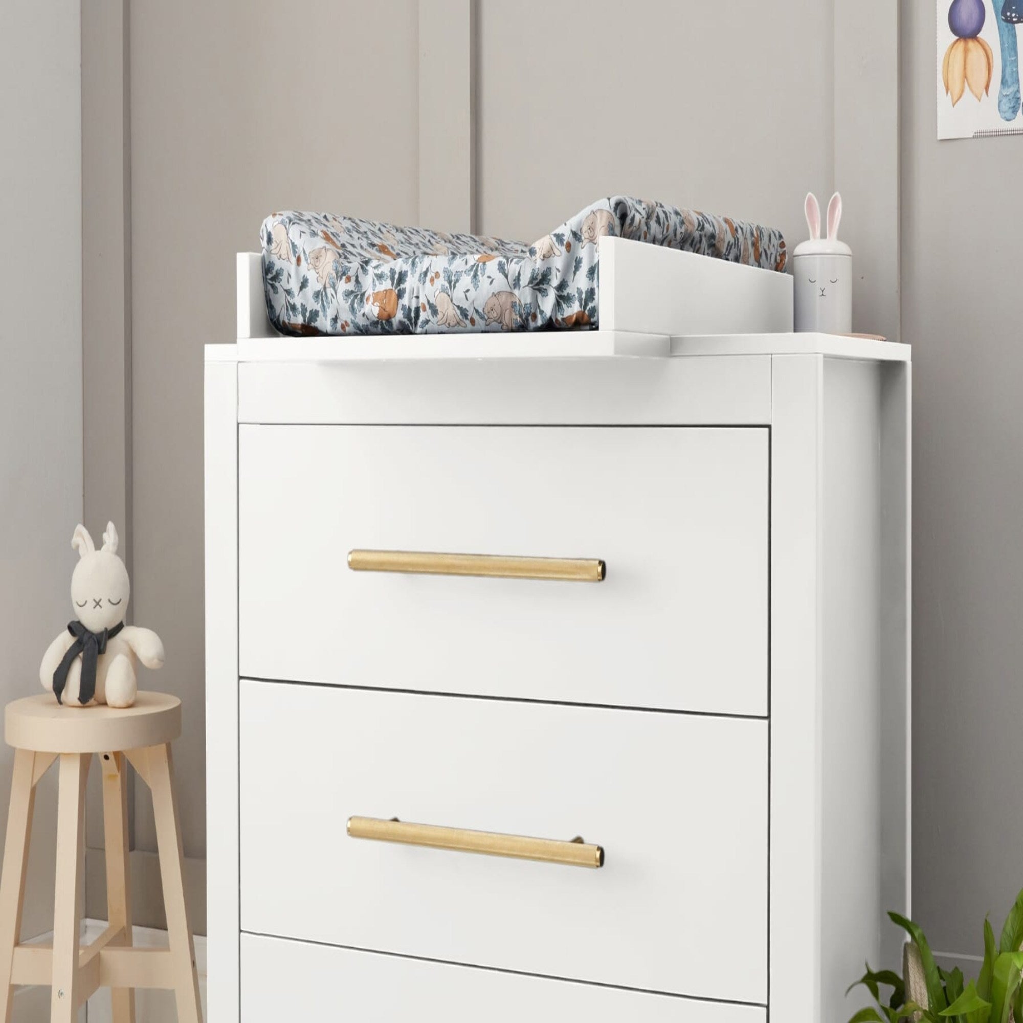 Angled lifestyle view of the Tivoli chest changer in white with removable changing top, highlighting spacious drawers and brushed brass handles