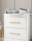 Angled lifestyle view of the Tivoli chest changer in white with removable changing top, highlighting spacious drawers and brushed brass handles