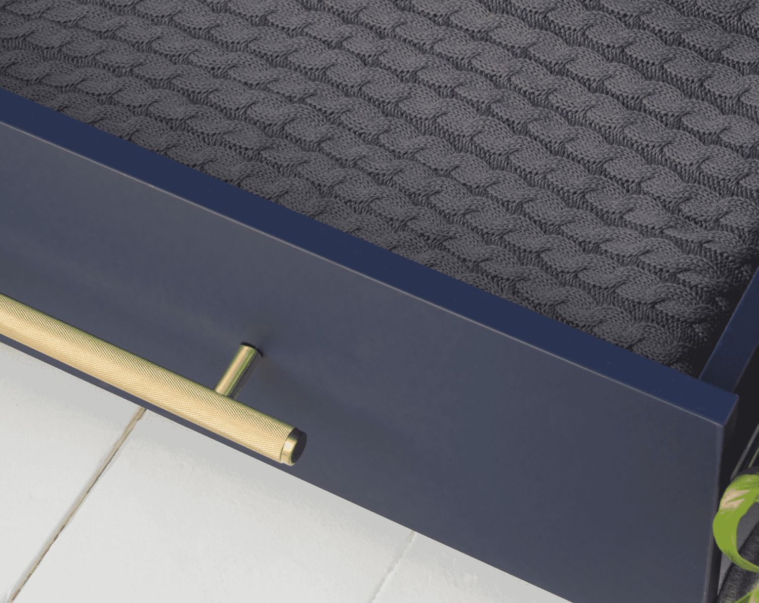 Close-up of the Tivoli chest changer drawer in navy showing textured gold handle and neatly folded knitted blanket inside