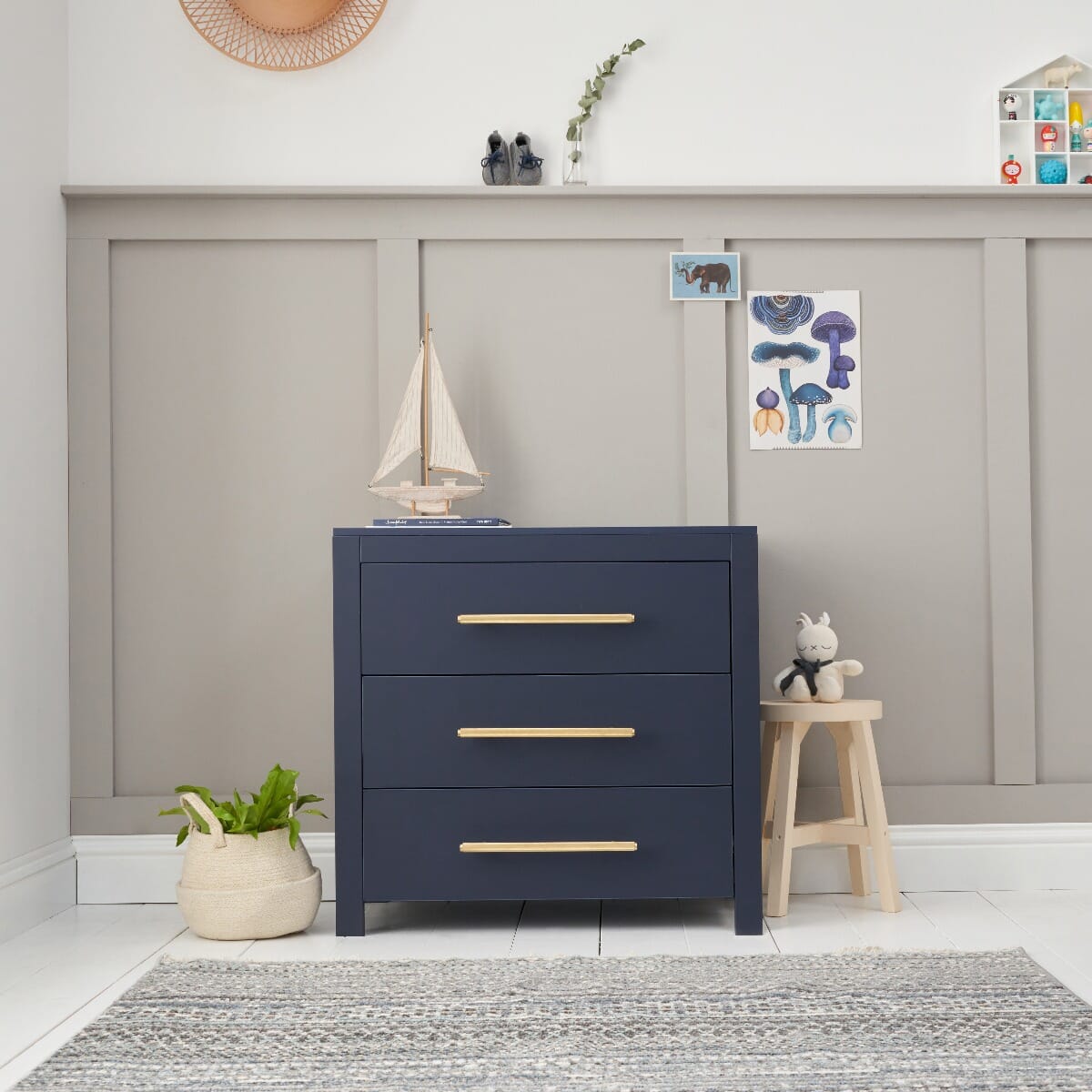 Front view of the Tivoli chest changer in navy with three spacious drawers and brushed gold handles, styled in a calm nursery setting