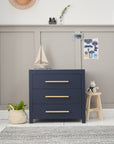 Front view of the Tivoli chest changer in navy with three spacious drawers and brushed gold handles, styled in a calm nursery setting