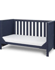 Angled view of the Tivoli cot bed in navy converted to sofa bed mode, showcasing slatted back and compact, versatile design