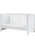 Angled view of the Tivoli cot bed in white in sofa bed mode, highlighting open sides and supportive base for daytime lounging