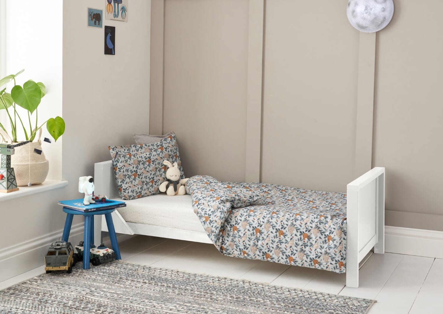 Tivoli cot bed converted to toddler bed in white, styled with patterned bedding and soft toys in a calm, child-friendly nursery setting