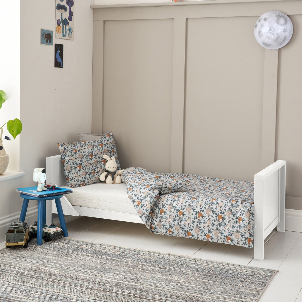 Lifestyle view of the Tivoli cot bed in white converted into a toddler bed, styled with patterned bedding in a calm, modern children’s room.