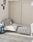 Lifestyle view of the Tivoli cot bed in white converted into a toddler bed, styled with patterned bedding in a calm, modern children’s room.