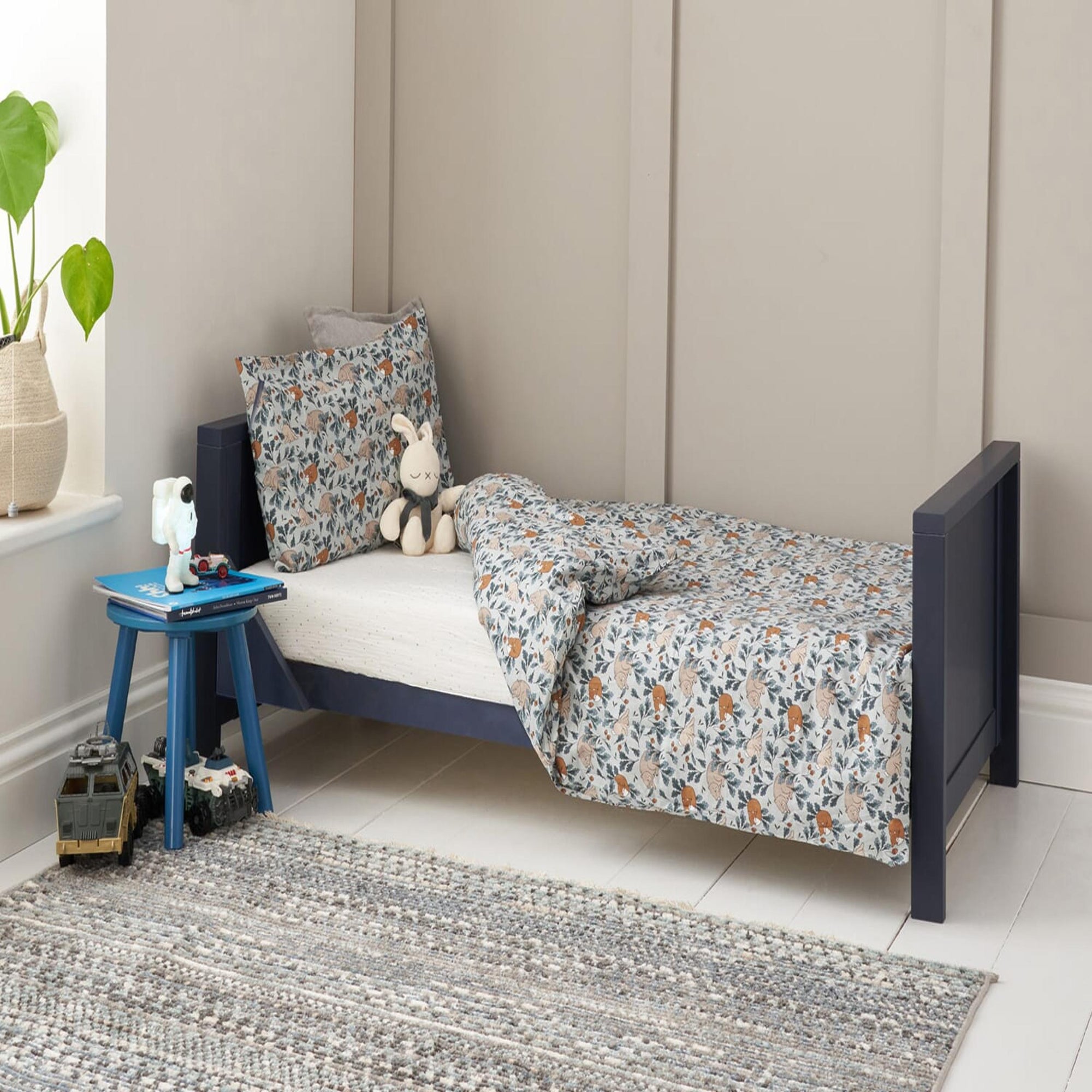 Tivoli cot bed in navy shown as a toddler bed in a styled bedroom, with low sides for easy access and a cosy sleep space
