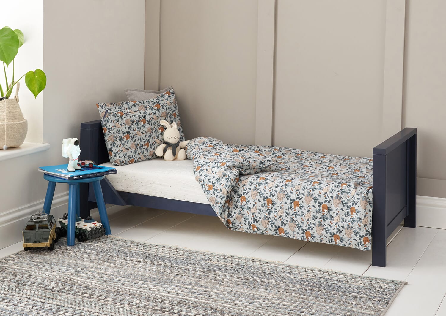 Tivoli cot bed in navy shown in toddler bed mode with woodland bedding, creating a cosy sleep space designed for comfort 