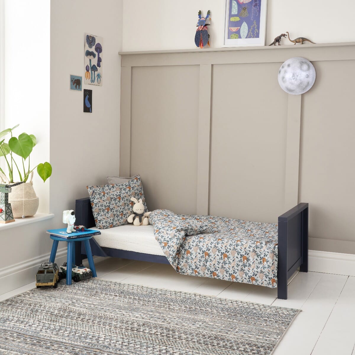 Tivoli cot bed in navy converted to toddler bed mode, styled with patterned bedding to create a calm and comfortable sleep space