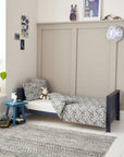 Tivoli cot bed in navy converted to toddler bed mode, styled with patterned bedding to create a calm and comfortable sleep space