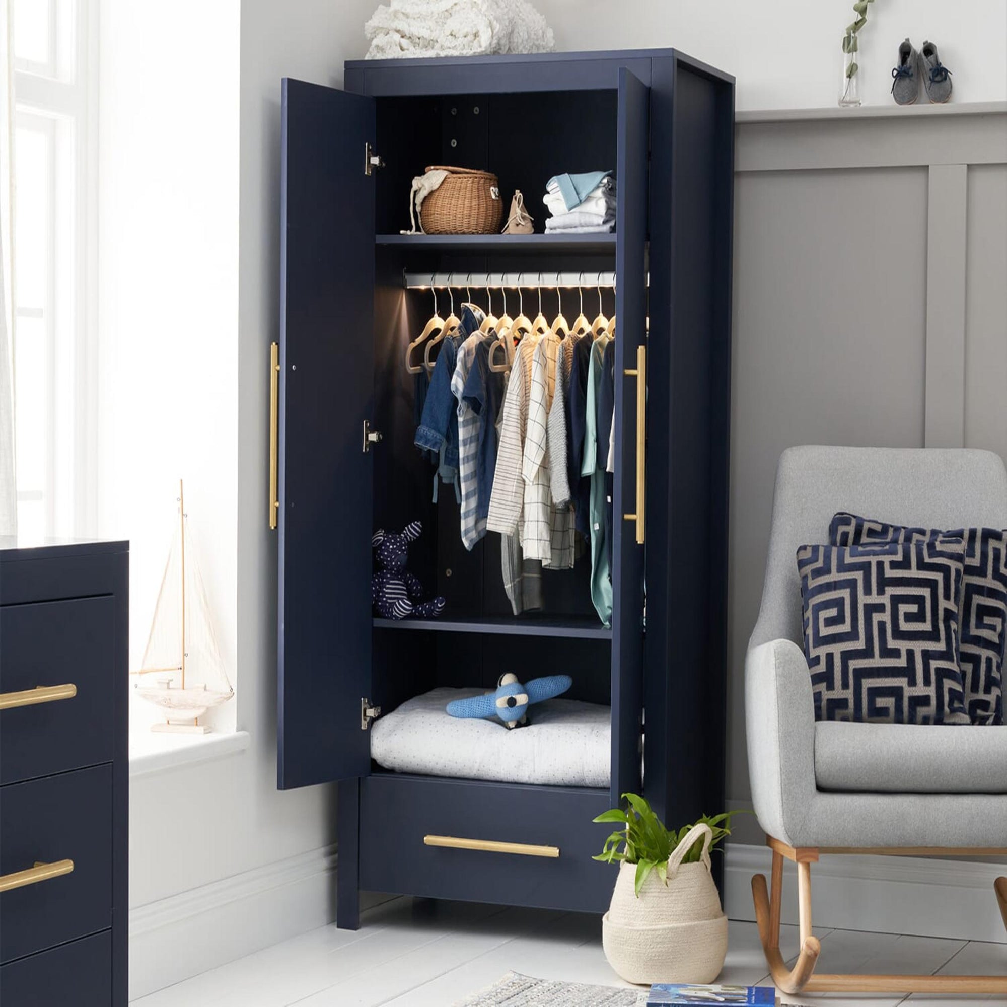 Tivoli wardrobe in navy with doors open, showing hanging rail, shelving and spacious drawer storage in a styled nursery setting