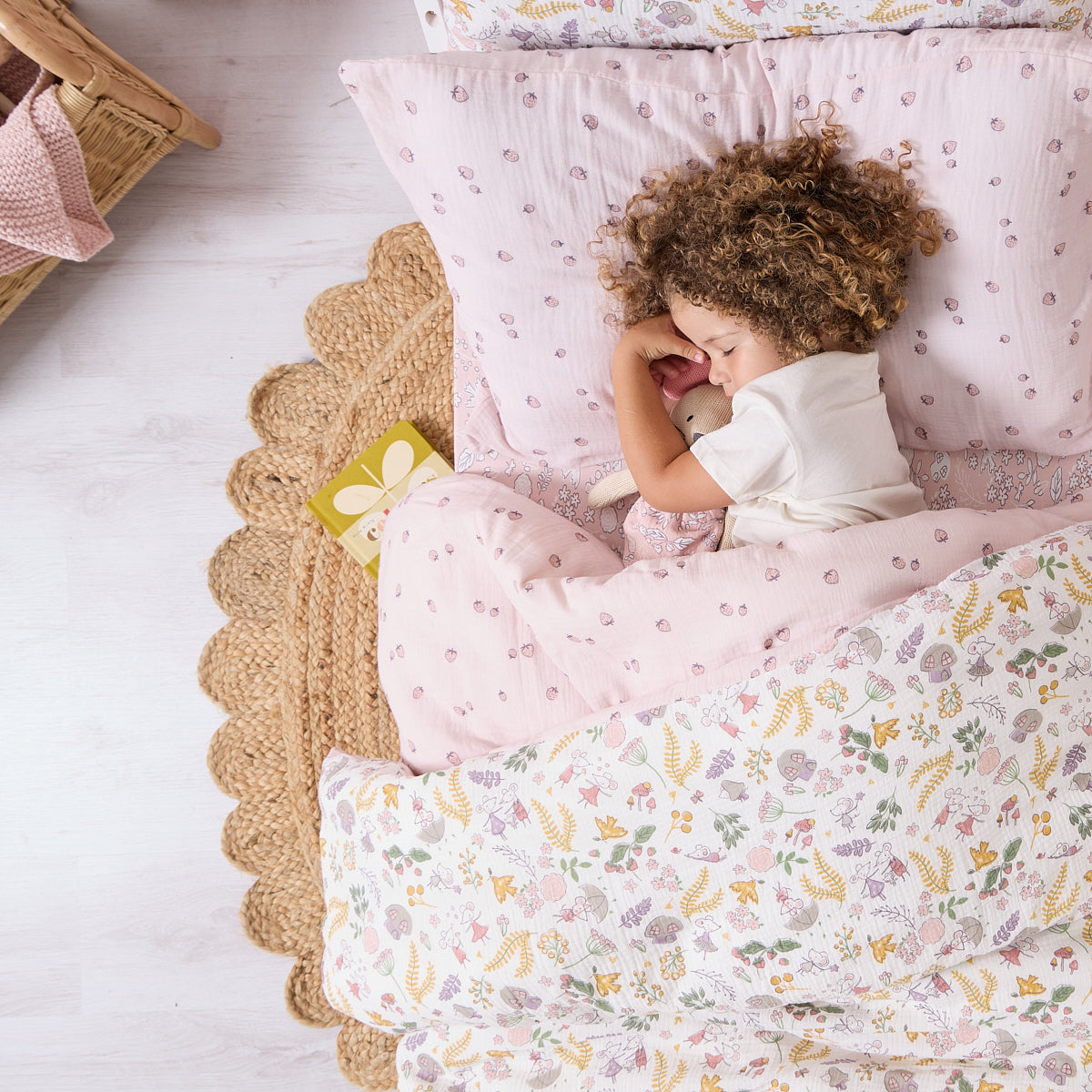 Toddler asleep under Tiny Tails single duvet cover and pillowcase set, showing reversible design with gentle woodland and berry-themed prints