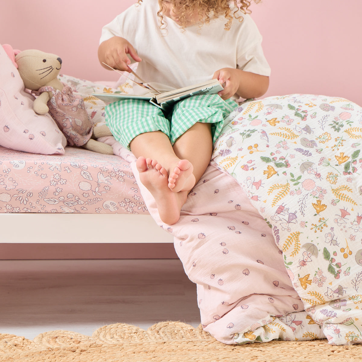 Toddler reading on Tiny Tails single duvet cover and pillowcase set with reversible woodland and strawberry prints in soft muslin fabric