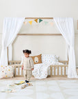 A girl standing next to the Casa Grande Toddler Bed Floor in a playful nursery