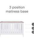 Close-up of Verona cot bed in white and oak demonstrating 3 adjustable mattress base heights for safe and convenient access as baby grows.