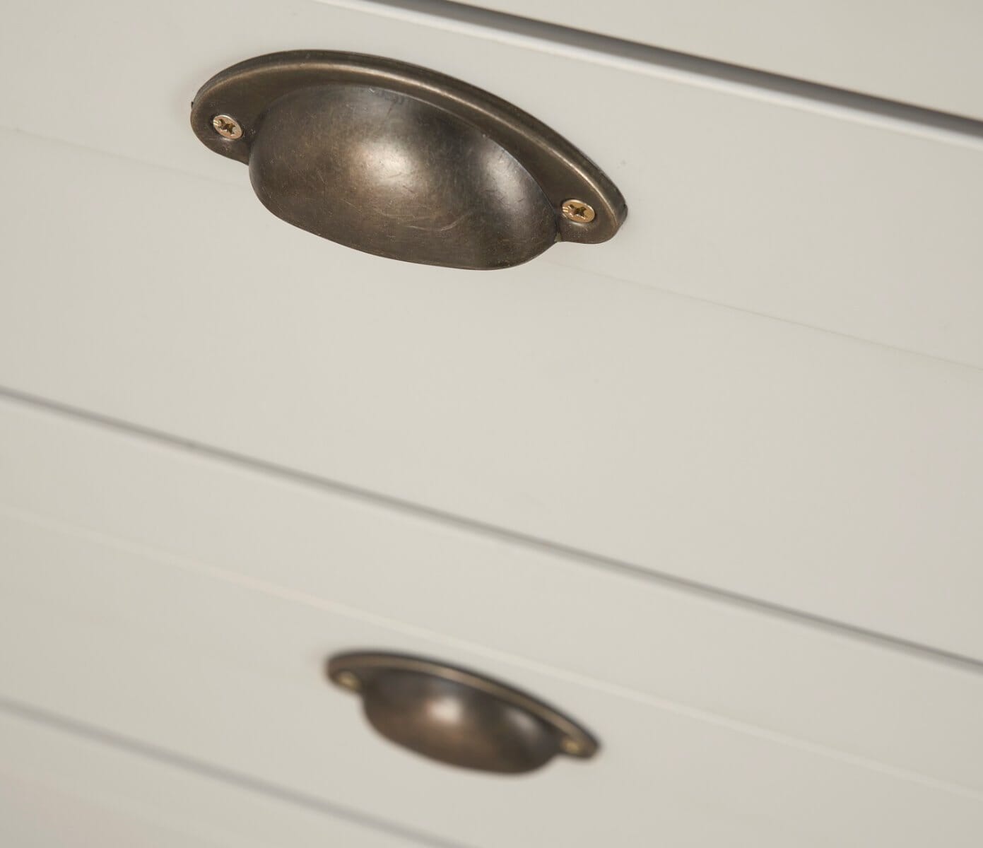 Close-up detail of the antique brass handles on the traditional shaker-style nursery furniture with a soft-touch finish.